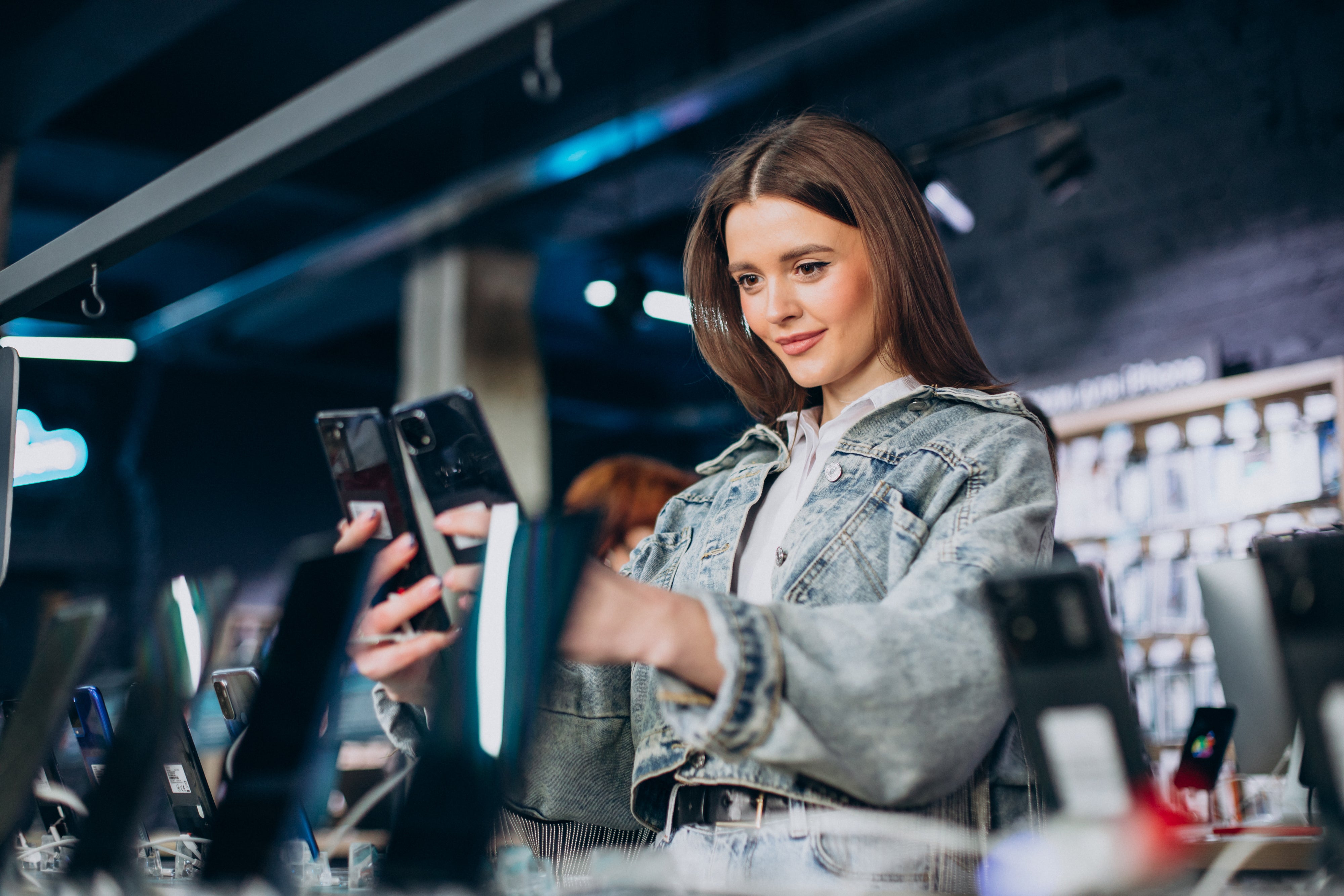 Woman in a store holding multiple smartphones